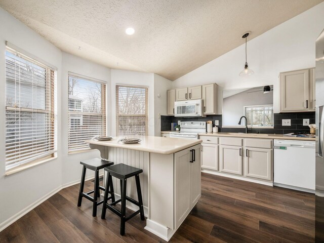 kitchen with vaulted ceiling, white appliances, a sink, and dark wood-style floors