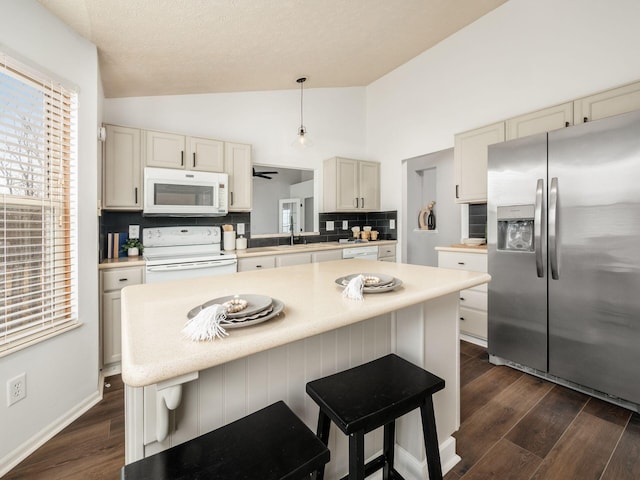 kitchen featuring lofted ceiling, white appliances, light countertops, and dark wood finished floors