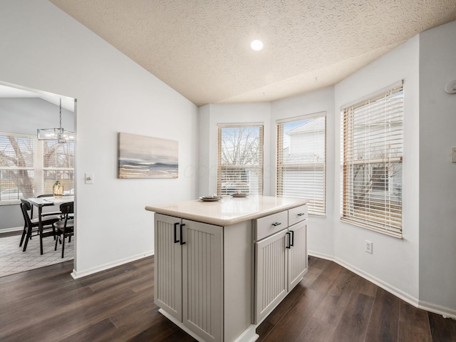 kitchen with dark wood-style floors, baseboards, vaulted ceiling, and a textured ceiling