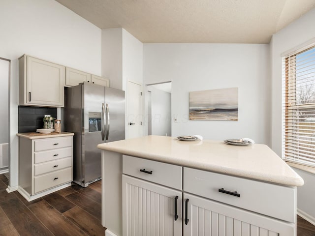 kitchen featuring dark wood-style floors, light countertops, visible vents, vaulted ceiling, and stainless steel fridge with ice dispenser