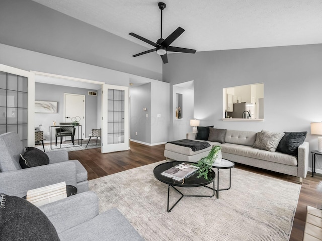 living area with lofted ceiling, ceiling fan, wood finished floors, and baseboards