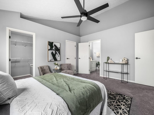 bedroom featuring carpet floors, a walk in closet, ensuite bathroom, vaulted ceiling, and baseboards