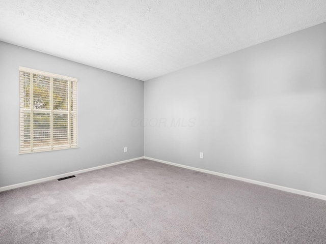 empty room featuring baseboards, carpet, visible vents, and a textured ceiling