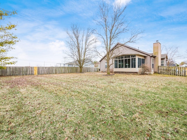 view of yard featuring a sunroom and a fenced backyard