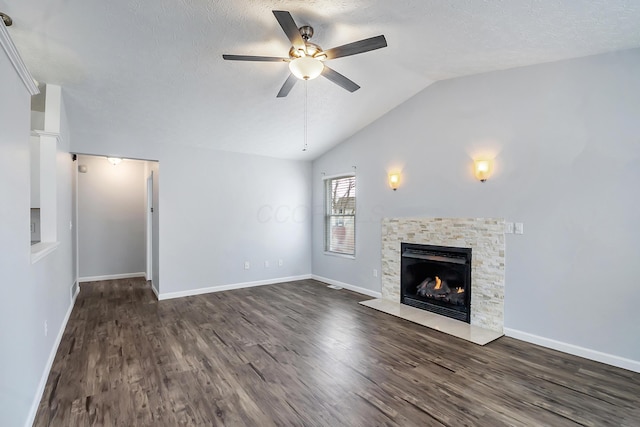 unfurnished living room with a textured ceiling, vaulted ceiling, dark wood-type flooring, and a stone fireplace