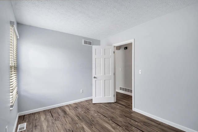 spare room with dark wood-style floors, baseboards, and visible vents