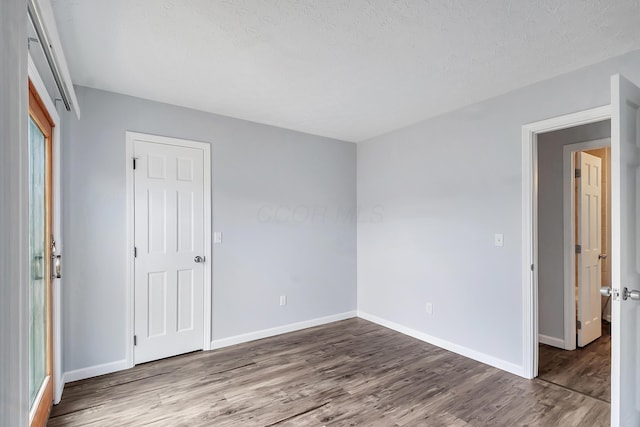 spare room featuring a textured ceiling, baseboards, and wood finished floors