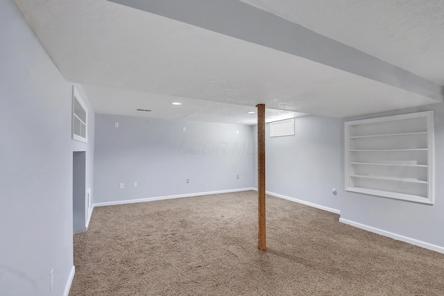 finished below grade area with a textured ceiling, recessed lighting, carpet floors, baseboards, and built in features