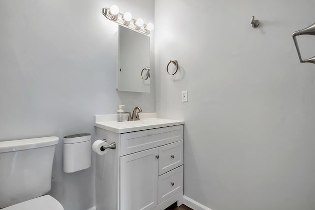 bathroom featuring toilet, baseboards, and vanity