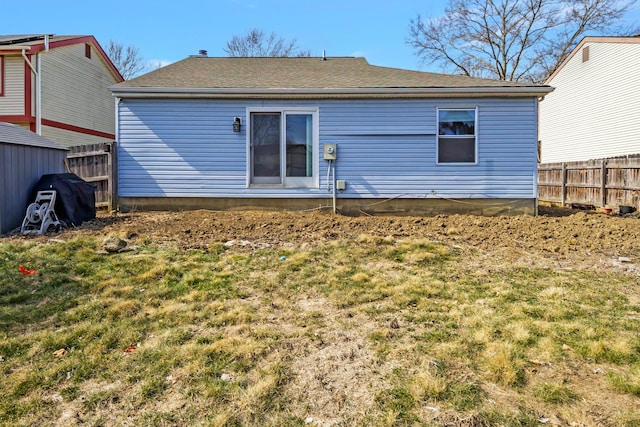 rear view of house with a lawn and fence