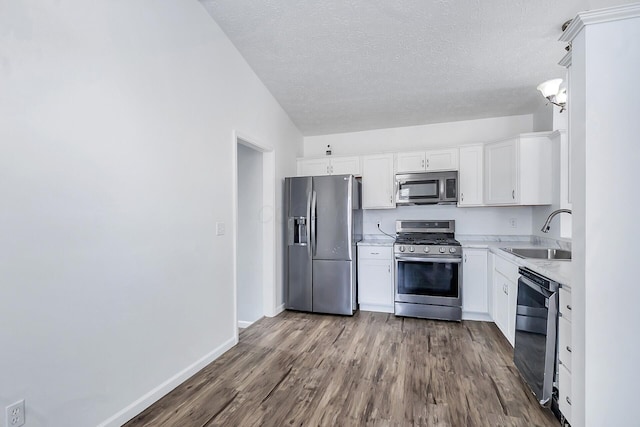 kitchen with dark wood-style floors, light countertops, appliances with stainless steel finishes, white cabinets, and a sink