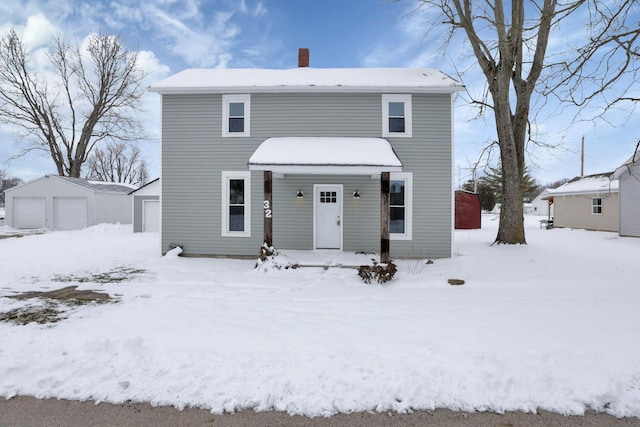 view of front of home with a chimney, a detached garage, and an outdoor structure