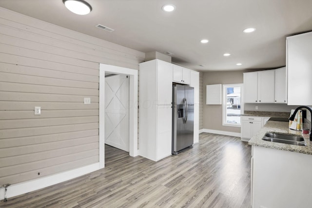 32 Railroad St, Jeffersonville, OH 43128 - kitchen with stainless steel refrigerator with ice dispenser, a sink, light stone countertops, white cabinets, and light wood-style flooring