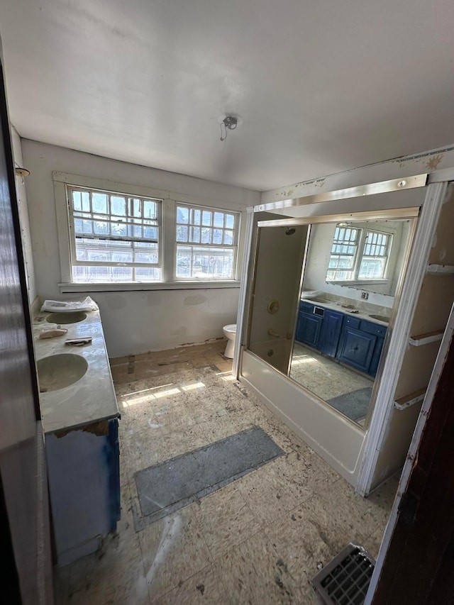 bathroom with a sink, toilet, and double vanity