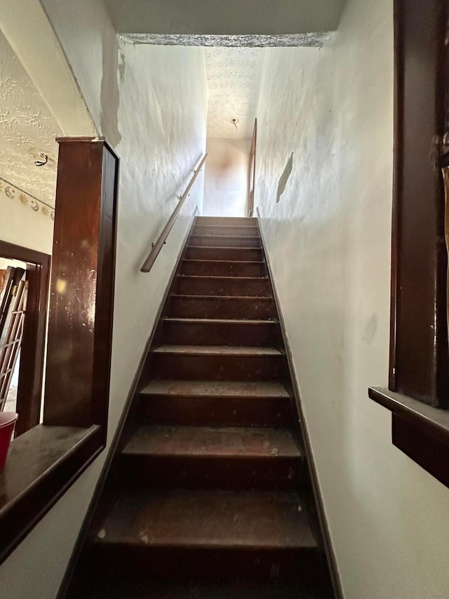 stairway featuring a textured ceiling