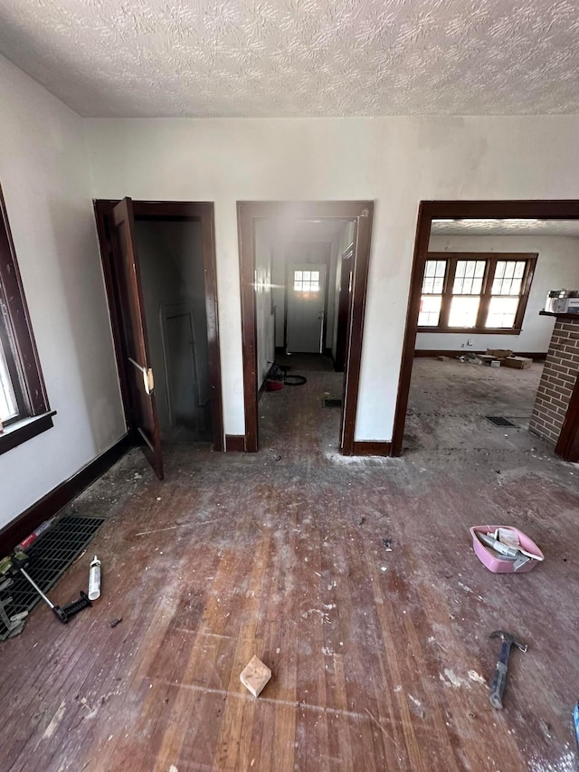 spare room featuring a textured ceiling, hardwood / wood-style floors, and baseboards