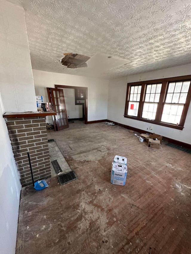 unfurnished living room featuring baseboards and a textured ceiling