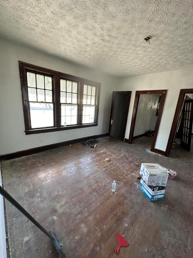 spare room with a textured ceiling and baseboards