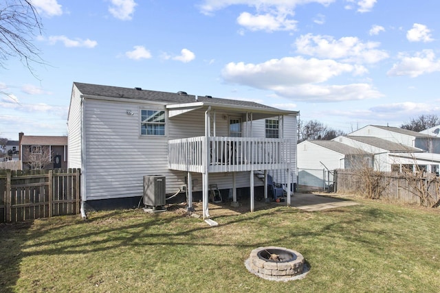 rear view of property featuring an outdoor fire pit, a lawn, central AC unit, and fence