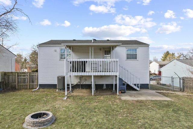 back of property with a deck, a yard, a fire pit, and fence