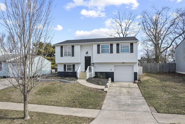 bi-level home with a garage, fence, concrete driveway, and a front yard