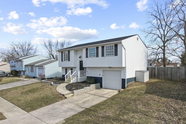 bi-level home with a garage, fence, concrete driveway, and a front yard