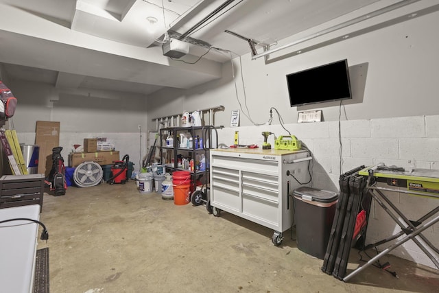 garage featuring a workshop area, concrete block wall, and a garage door opener