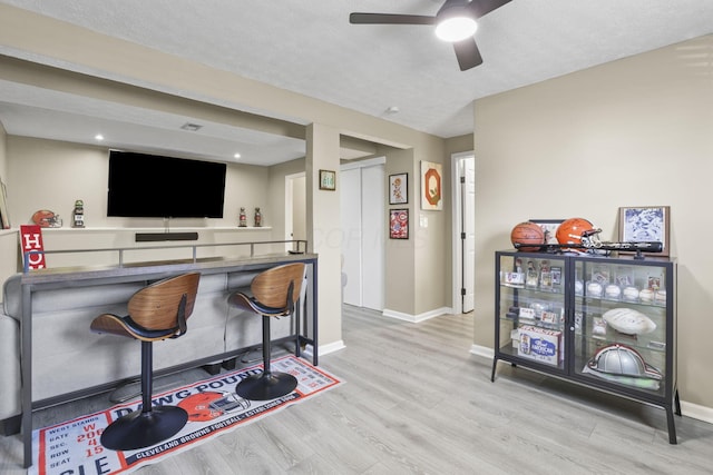 bar with a textured ceiling, wood finished floors, a ceiling fan, and baseboards