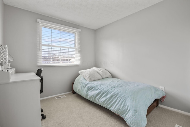 bedroom with carpet, visible vents, a textured ceiling, and baseboards