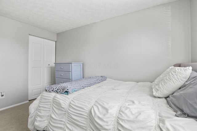 carpeted bedroom featuring a textured ceiling, baseboards, and a closet