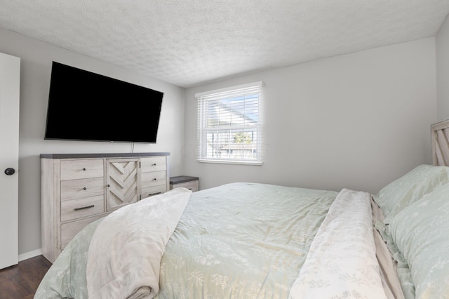 bedroom featuring dark wood-style floors, baseboards, and a textured ceiling