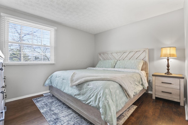 bedroom with a textured ceiling, baseboards, and wood finished floors