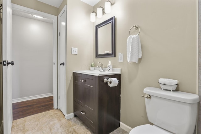 bathroom with toilet, baseboards, and vanity