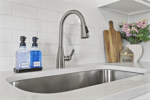 interior details with tasteful backsplash, a sink, and light stone counters