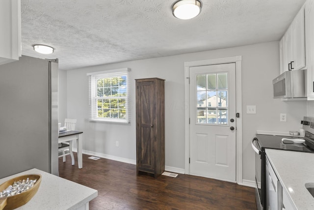 kitchen featuring stainless steel appliances, dark wood-style flooring, visible vents, white cabinetry, and baseboards