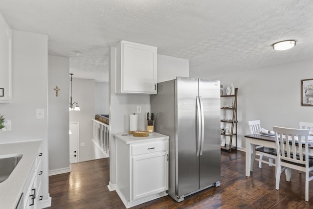 kitchen featuring dark wood finished floors, light countertops, freestanding refrigerator, white cabinets, and baseboards