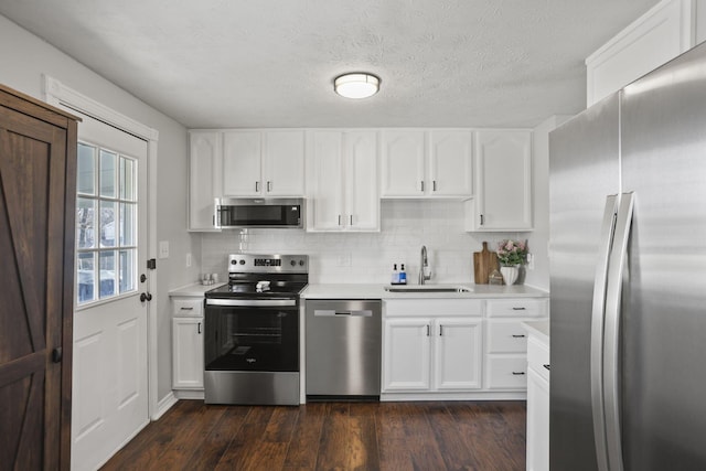 kitchen with appliances with stainless steel finishes, dark wood-style flooring, light countertops, and a sink