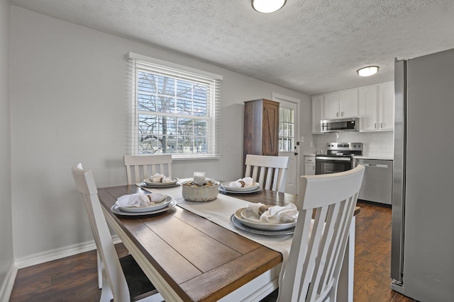 dining space with a textured ceiling, baseboards, and dark wood-type flooring