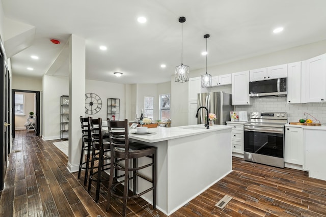 kitchen featuring stainless steel appliances, dark wood-style flooring, a sink, and tasteful backsplash