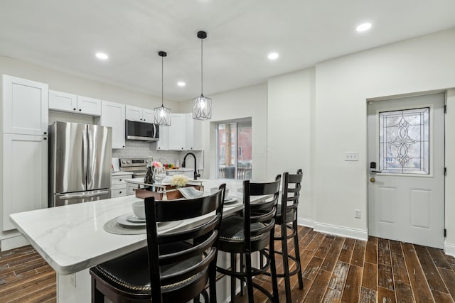 kitchen featuring an island with sink, backsplash, stainless steel appliances, and dark wood finished floors