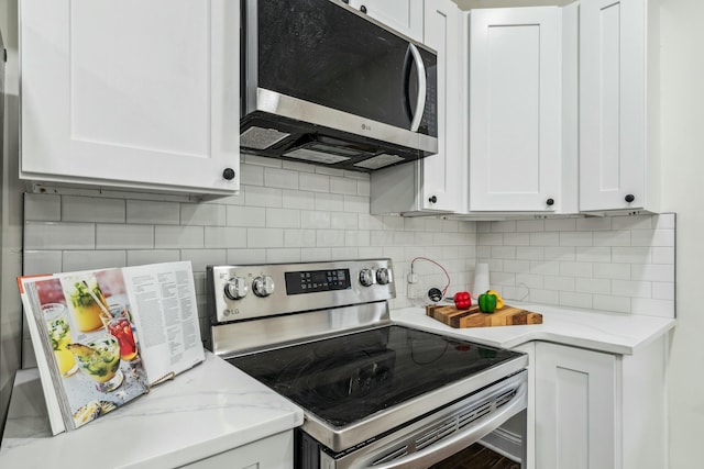 kitchen featuring appliances with stainless steel finishes, white cabinets, backsplash, and light stone countertops