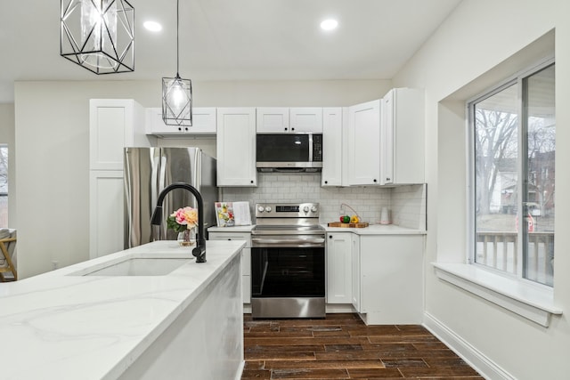 kitchen with white cabinets, appliances with stainless steel finishes, backsplash, wood finish floors, and a sink