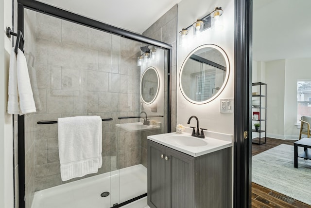 bathroom with baseboards, a shower stall, vanity, and wood finished floors