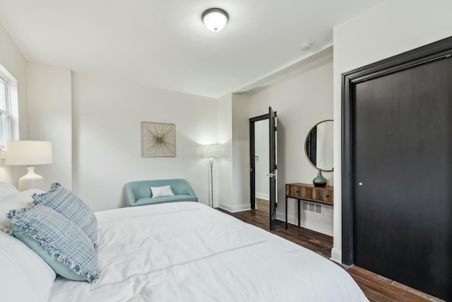 bedroom with baseboards and dark wood-type flooring