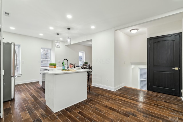 kitchen featuring dark wood finished floors, a center island with sink, light countertops, visible vents, and freestanding refrigerator