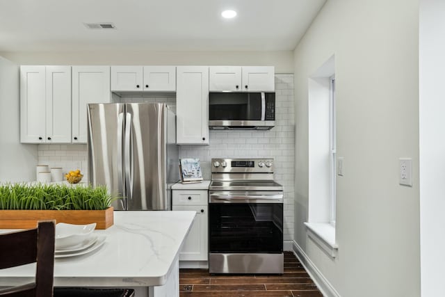 kitchen with visible vents, light stone counters, appliances with stainless steel finishes, dark wood-type flooring, and backsplash