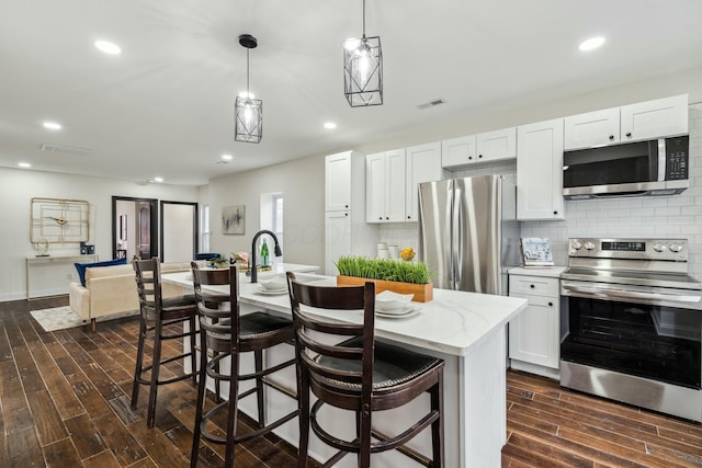 kitchen featuring visible vents, decorative backsplash, dark wood-type flooring, stainless steel appliances, and white cabinetry