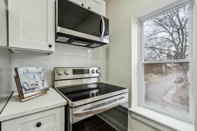 kitchen featuring stainless steel appliances, white cabinetry, and decorative backsplash