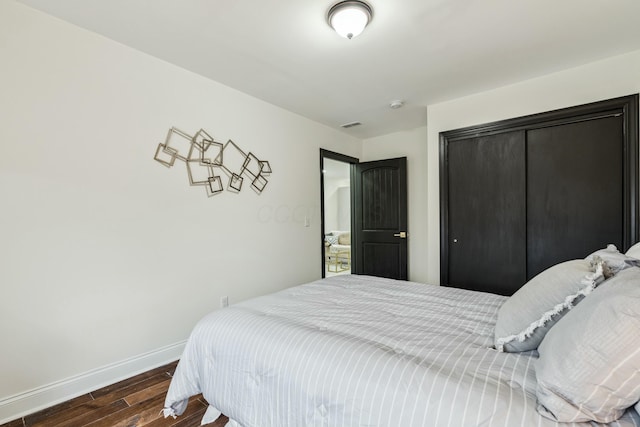 bedroom with a closet, visible vents, baseboards, and wood finished floors