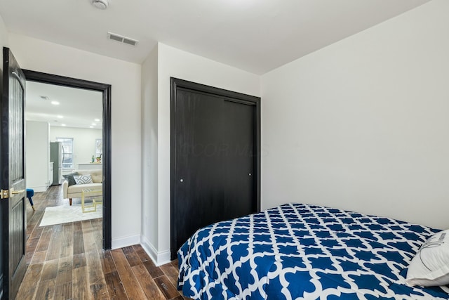 bedroom featuring dark wood-style flooring, a closet, visible vents, and baseboards